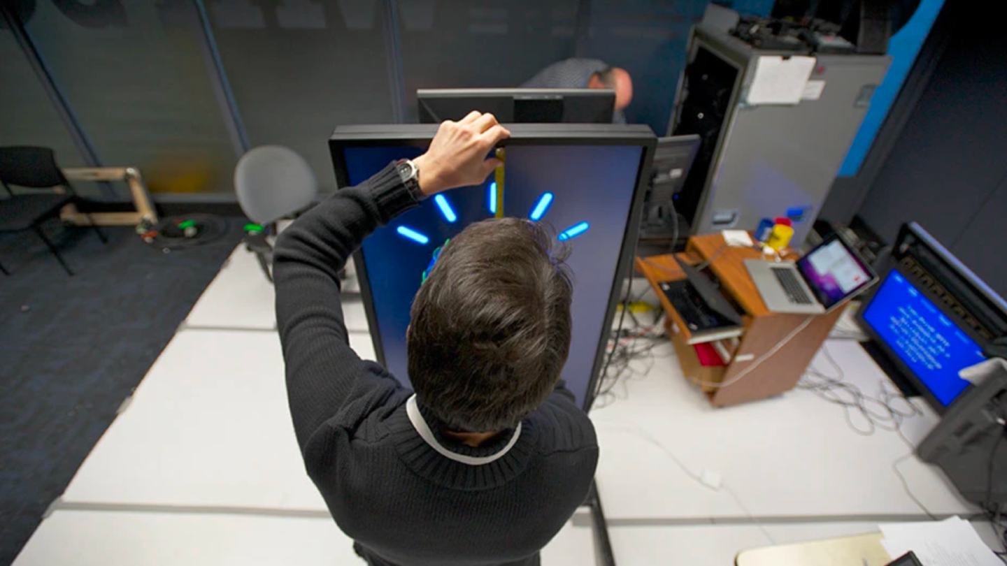 An IBM researcher measures the avatar display panel with a tape measure in the IBM Watson testing lab.